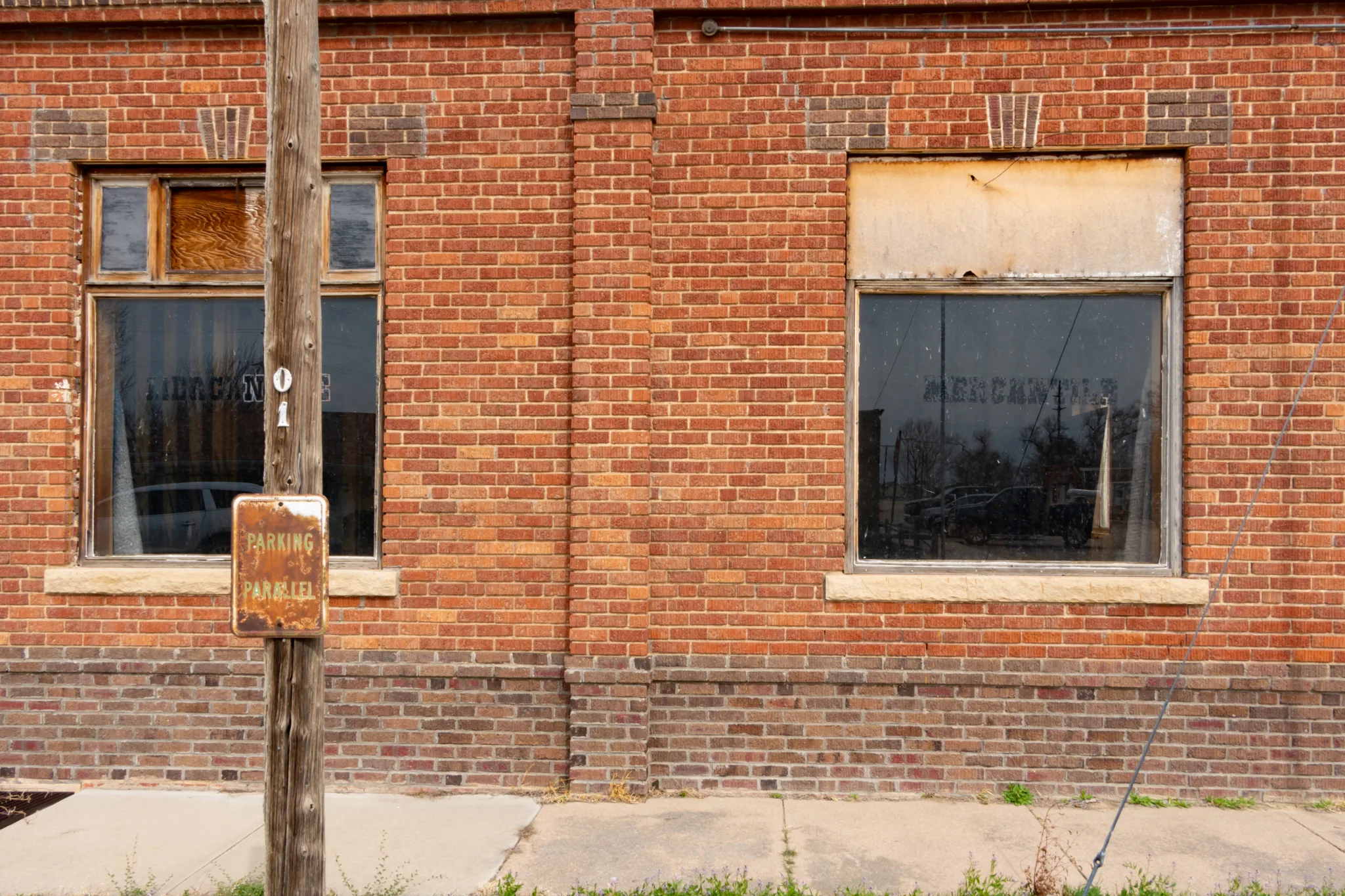 Close up of an abandoned Merchantile building in Hillrose, Colorado. In the window you can see a reflection of cars parked in the business district.